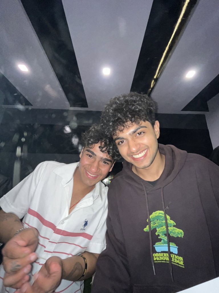 Two friends smiling together under striped ceiling lights